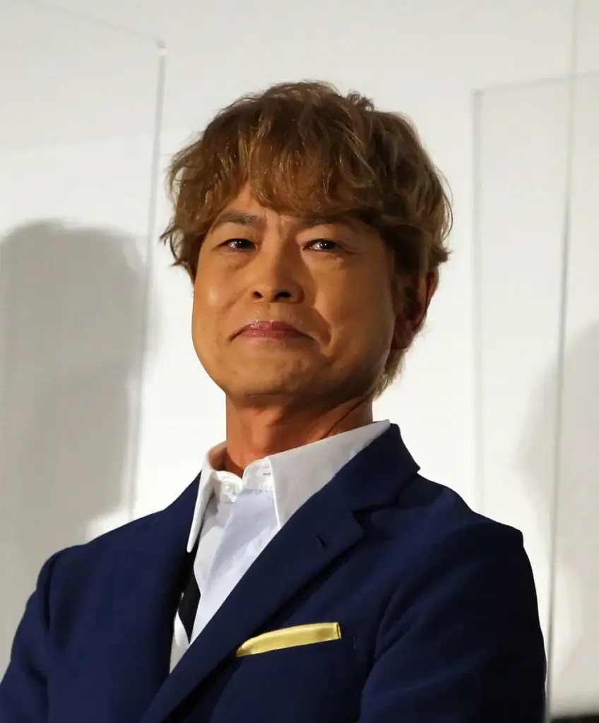 "イベントに登壇し、少し硬い表情でカメラを見つめる茶髪の古谷徹さん"