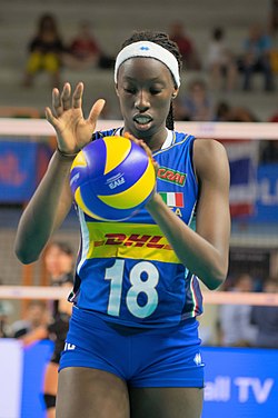 青いユニフォームを着たバレーボール選手がボールを両手で持っている様子です。