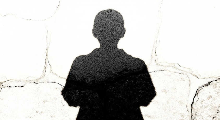 白いひび割れた壁に、腕を組んだ人物の黒い影が焼き付いたように見える、原爆の熱線を想起させる画像です