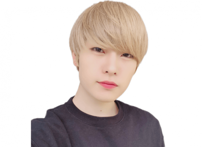 金髪のショートヘアで、黒い服を着た日本人男性のバストアップ画像です。