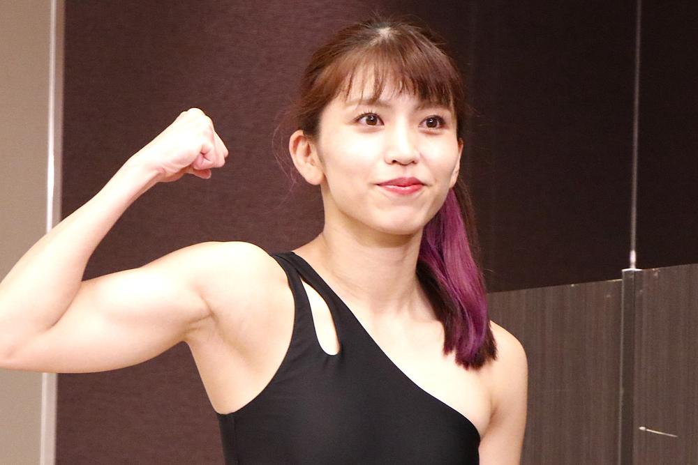 黒い服を着て、力こぶを見せている日本人女性のポートレート。