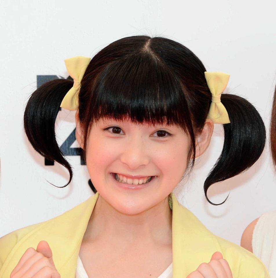 黄色のリボンでツインテールに髪を結び、笑顔を見せている女性の顔のアップ。