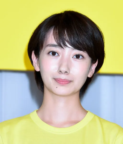 短いボブヘアの日本人女性が、黄色い背景の前で笑顔を見せています。
