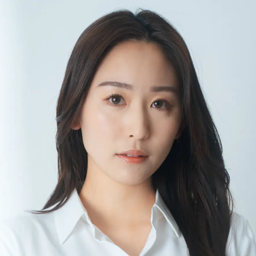 白いシャツを着た、落ち着いた表情のロングヘアの日本人女性のポートレート。