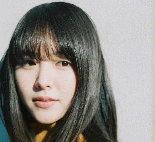 「温かみのある光の中でカメラを見つめる日本人女性のアップ」
