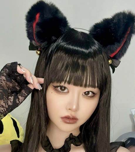 黒い猫耳のカチューシャをつけてポーズをとる日本人女性