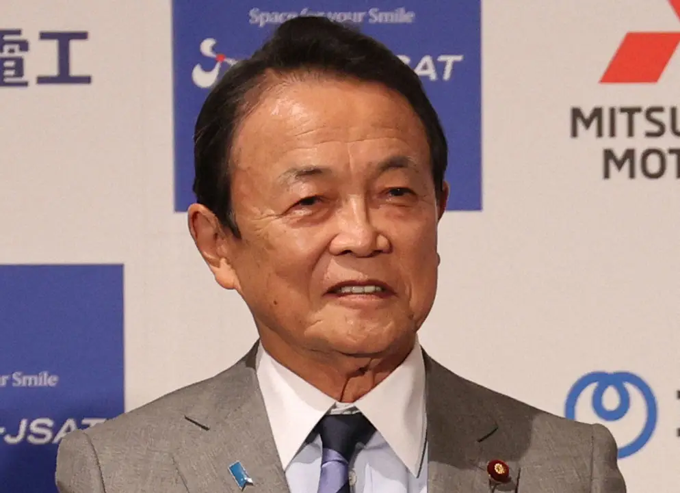 記者会見場またはフォーマルな背景で撮影された、麻生太郎氏の胸から上のポートレート写真。