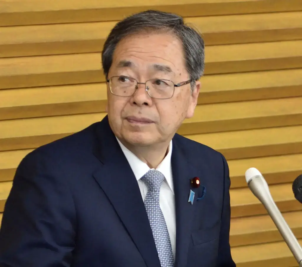 スーツとメガネを着用した斉藤鉄夫氏が、マイクの前で会見に臨んでいる様子のクローズアップ写真。