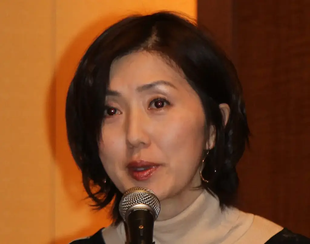フジテレビアナウンサーの佐々木恭子さん。ベージュのタートルネックセーターを着用し、マイクの前で真剣な表情でスピーチをしている様子。