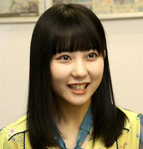 黄色い衣装を着て笑顔を見せる田中美久さんの写真。