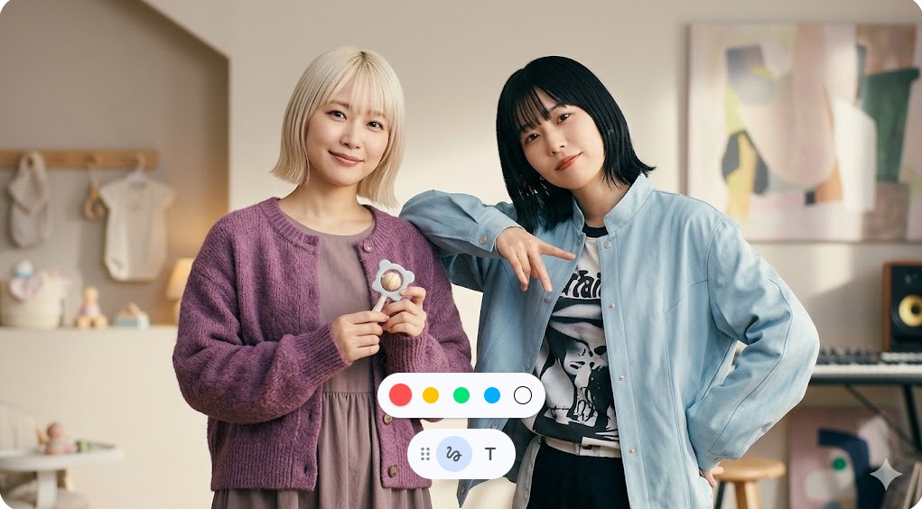 赤ちゃんのおもちゃを手に微笑む金髪の女性と、彼女の肩に寄り添う黒髪の女性