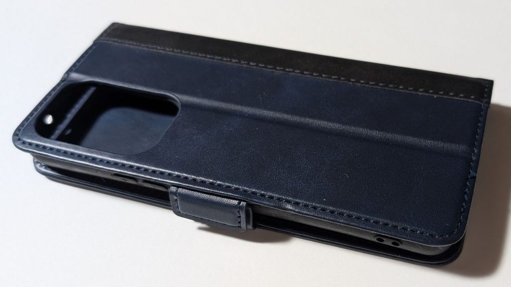 黒い手帳型スマホケースの背面。カメラ用の開口部や留め具、表面のステッチが見える