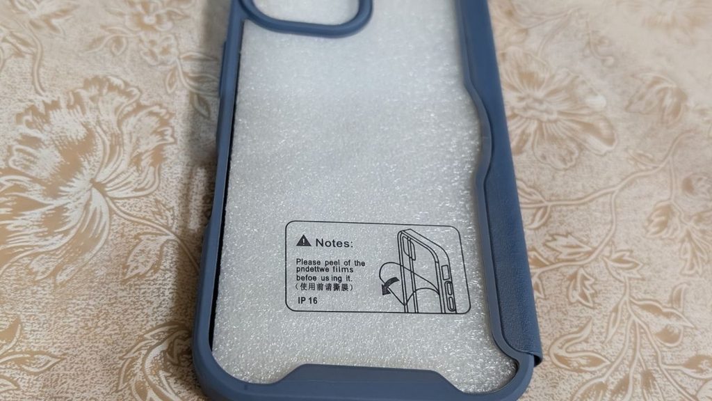 青みのあるスマホケースの内側に白い保護材が入り、保護フィルムの注意シールが貼られている写真